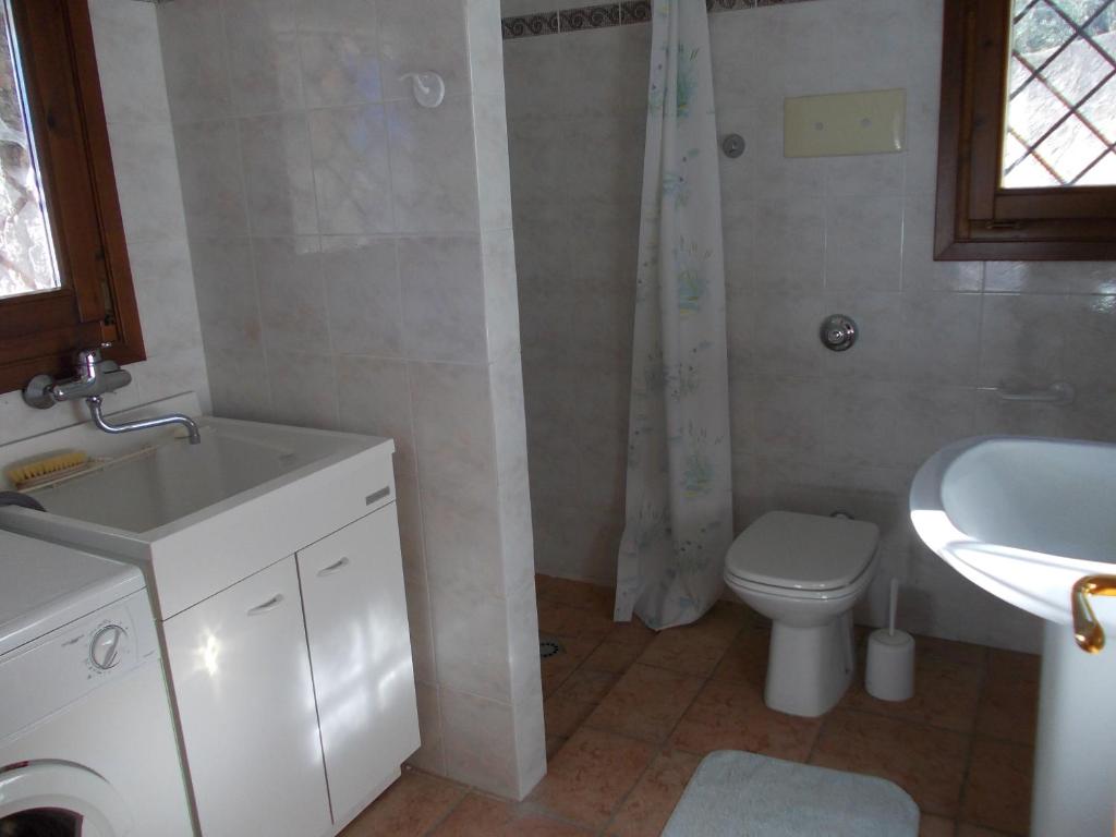La salle de bains est pourvue d'un lavabo blanc et de toilettes. dans l'établissement Villa Venturelli, à Tignale