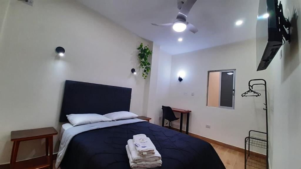 a bedroom with a bed with a blue blanket and a spotlight at Gran Imperial Avenida in Tumbes