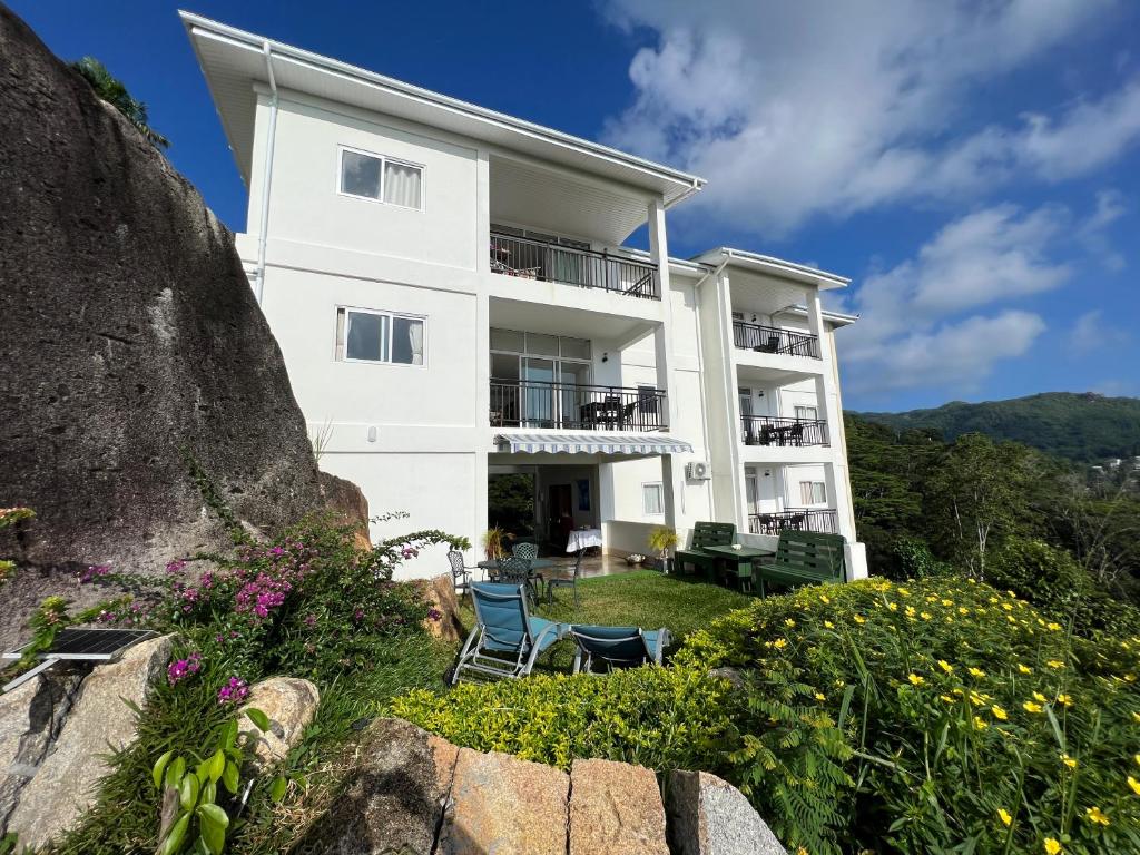 - un grand bâtiment blanc avec des chaises et des fleurs dans l'établissement Creole Pearl Self-Catering, à Victoria