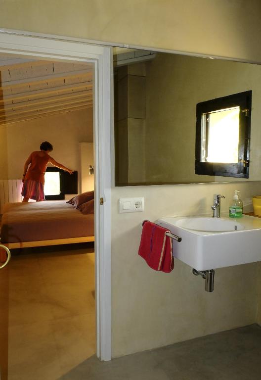 Un baño con lavabo, espejo y cama. en Ca L'Olier, en Montblanquet