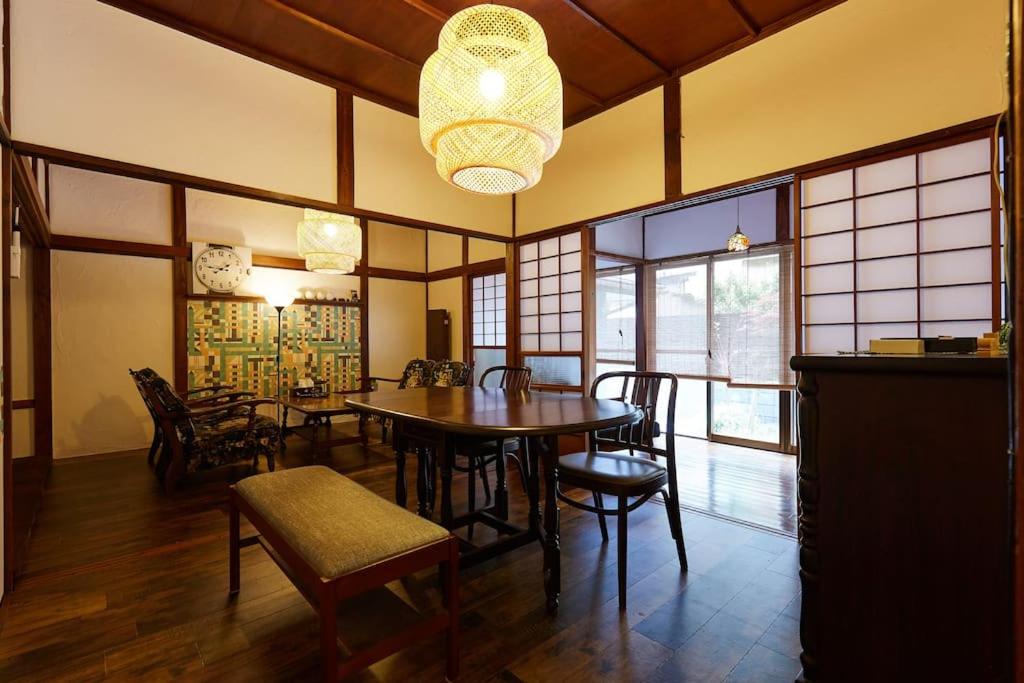 een eetkamer met een tafel en stoelen en een kroonluchter bij EK House Kamakura 鎌倉 Free Parking in Kamakura