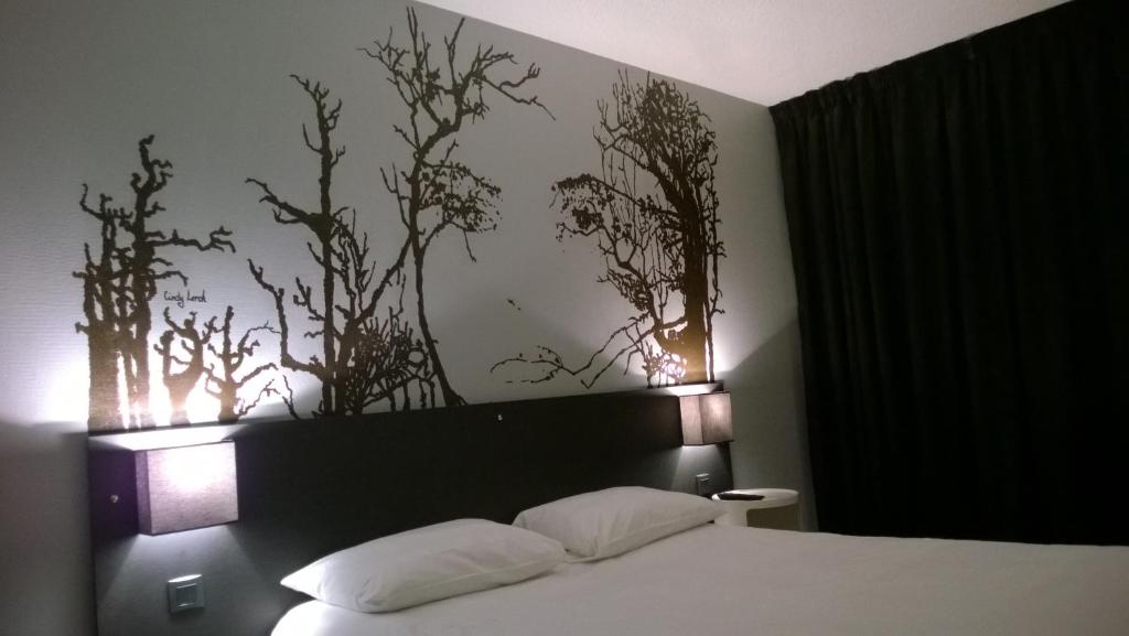 um quarto com uma cama com árvores na parede em Dav'hotel Jaude em Clermont-Ferrand