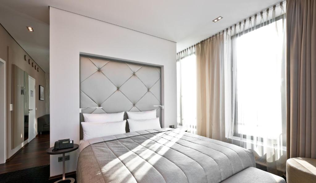 a bedroom with a large bed and a large window at COSMO Hotel Berlin Mitte in Berlin