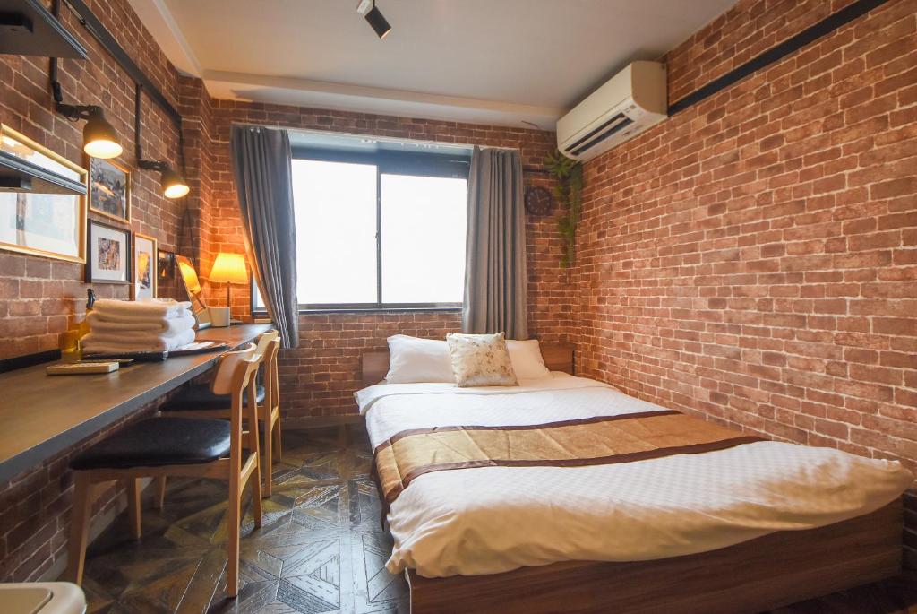 a bedroom with two beds and a brick wall at Comfy Stay Sakuramachi in Nara