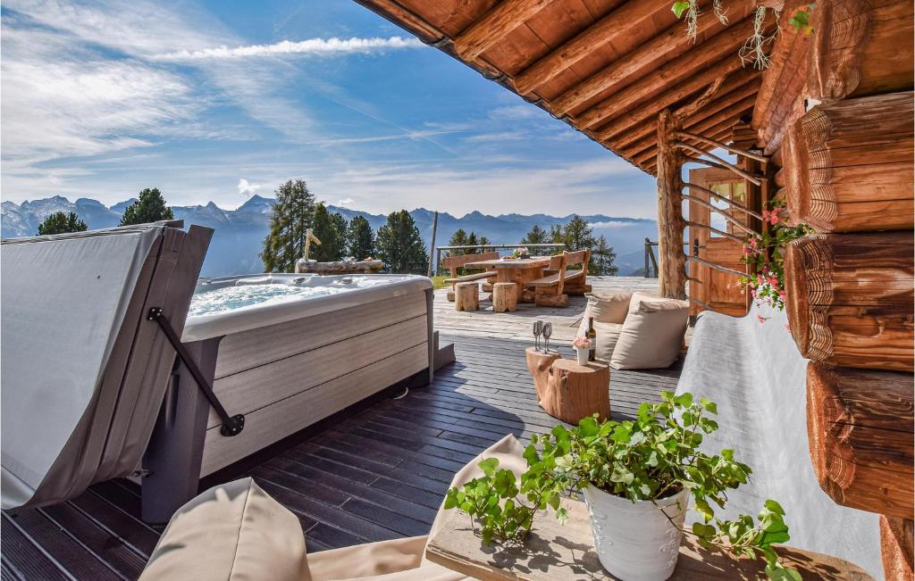 una bañera de hidromasaje en una terraza con montañas al fondo en Chalet Luisa, en Predazzo