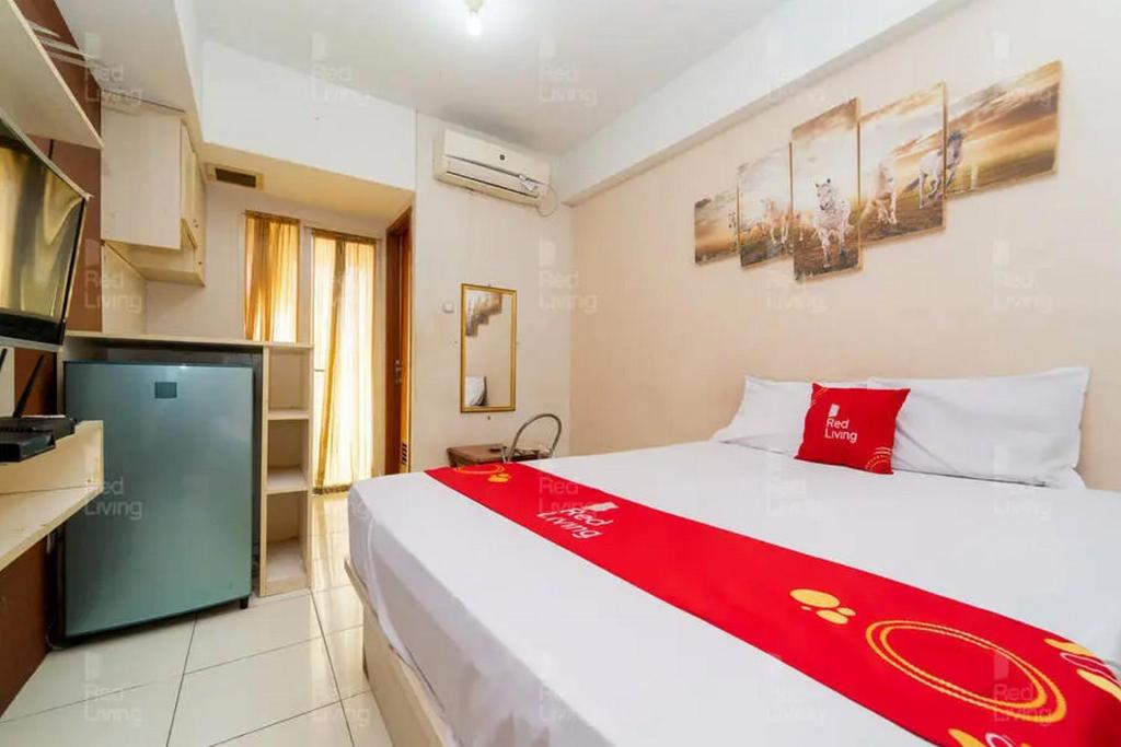 a bedroom with a bed with a red blanket on it at RedLiving Apartemen Green Lake View Ciputat - Pelangi Rooms 1 Tower E in Pondokcabe Hilir