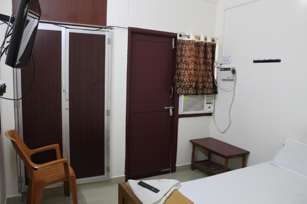 Habitación con cama, TV y puerta. en Agp Homestay en Chennai
