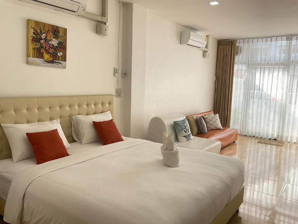 a bedroom with a large white bed and a couch at Na cha lae 2 in Chanthaburi