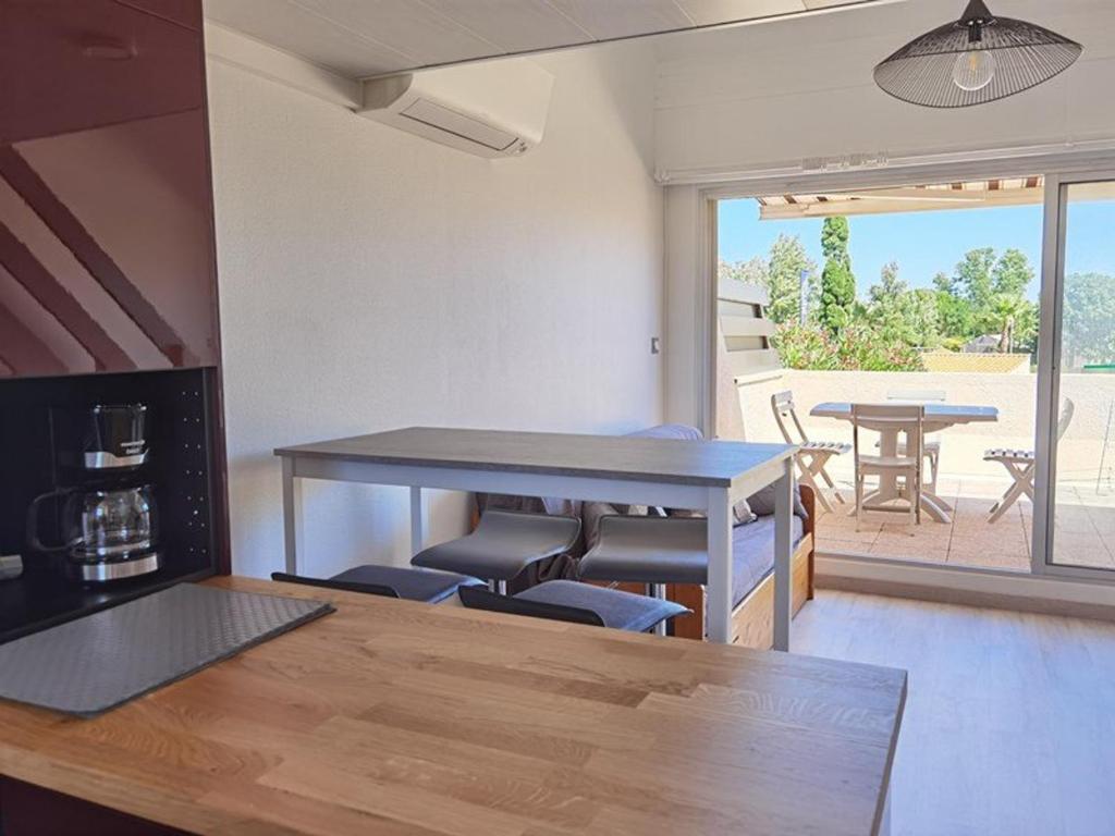 Il dispose d'une terrasse et d'une cuisine avec une table et des chaises. dans l'établissement Appartement Climatisé 2 Pièces avec Terrasse et Parking - Classé 2 Étoiles - FR-1-326-690, à Marseillan
