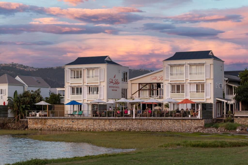 a building with tables and umbrellas next to a body of water at The Lofts Boutique Hotel in Knysna