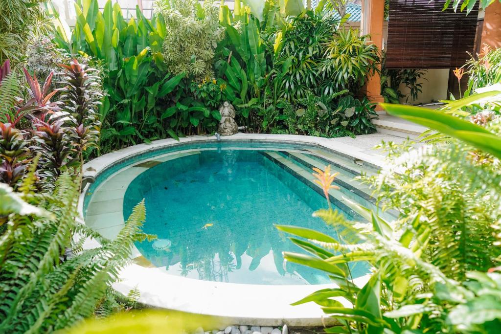 a swimming pool in the middle of a garden at Villa Bumi Ayu Sanur in Sanur