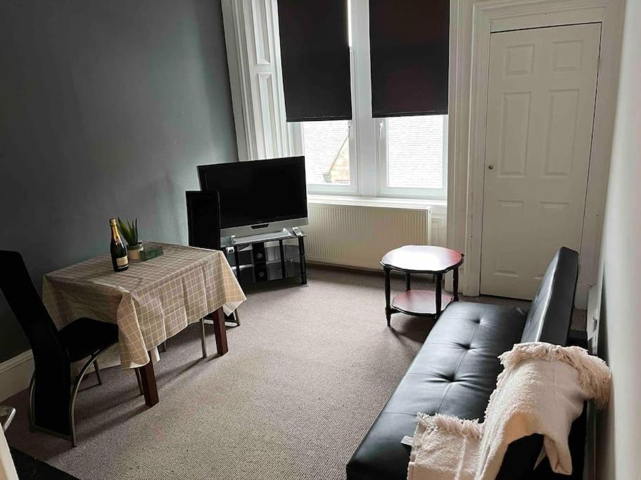 ein Wohnzimmer mit einem Sofa und einem Tisch in der Unterkunft Centrally located 1 bed flat with furnishings & white goods. in Gourock