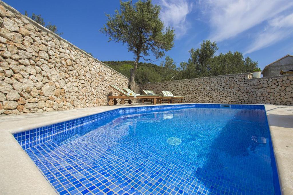 a swimming pool in front of a stone wall at Villa Burica in Vinišće