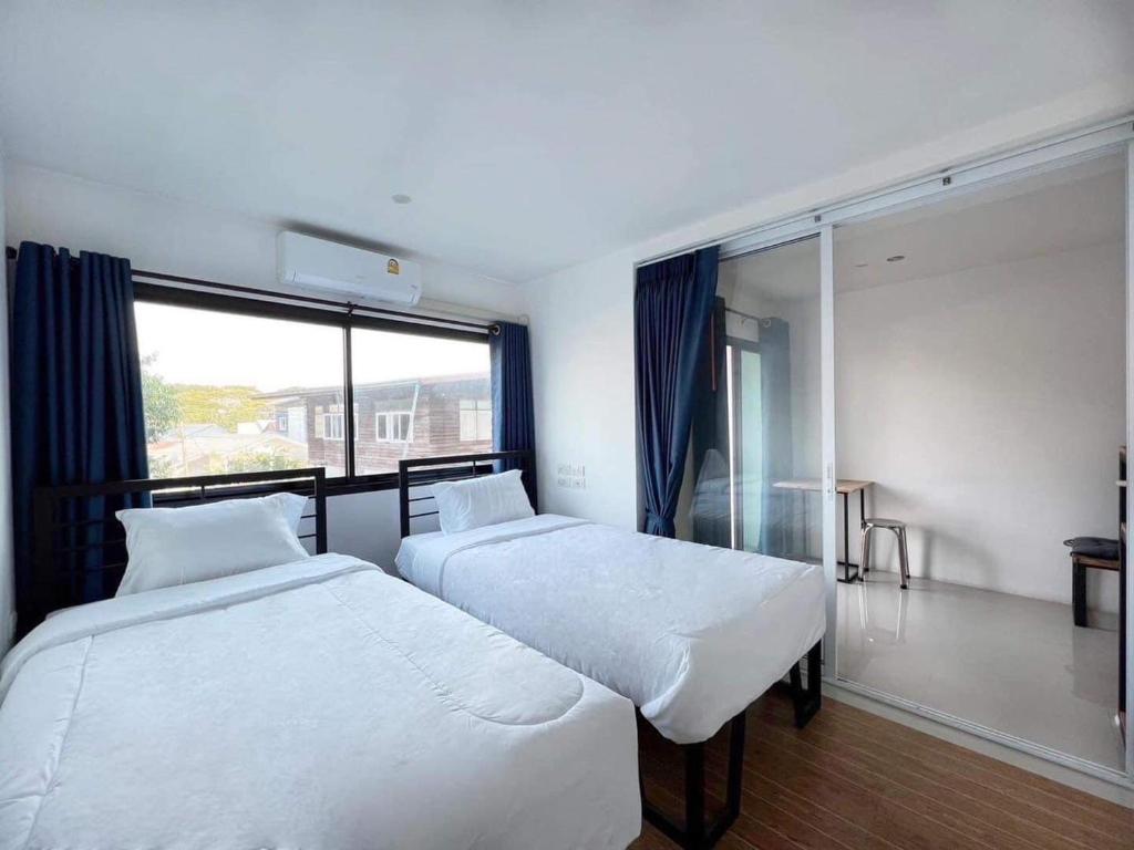 two beds in a room with a large window at Dm-udon (ดีเอ็ม อุดรธานี) in Udon Thani