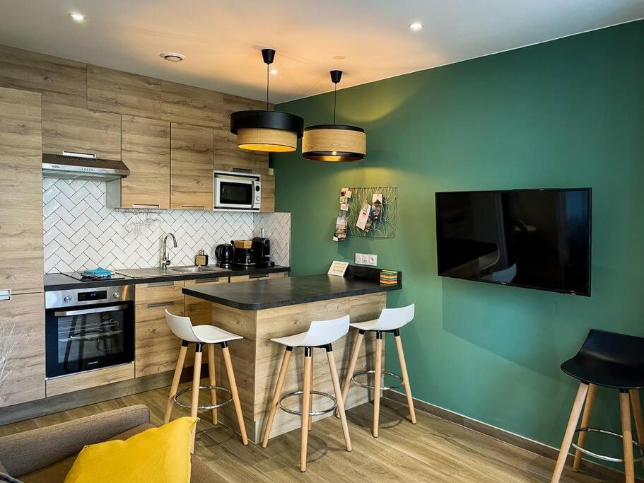 a kitchen with green walls and a bar with stools at Apt RDC avec sa terrasse privée in Saint Malo