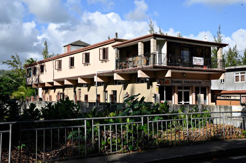 a large white building with a fence in front of it at Riambel Paradise Inn First Floor Room in Riambel