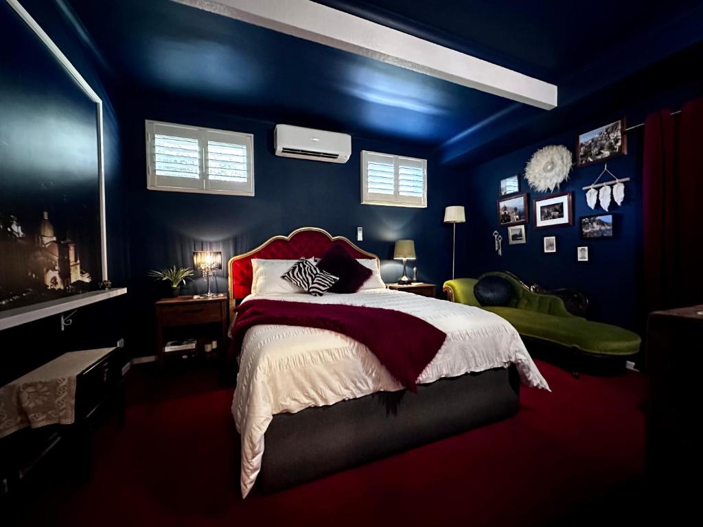 Schlafzimmer mit blauen Wänden und einem Bett mit roter Bettwäsche in der Unterkunft Arthurs Seat Cottage - Sulla Collina in Arthurs Seat