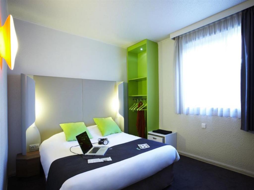 a hotel room with a bed with a laptop on it at Campanile Auxerre - Monéteau in Monéteau