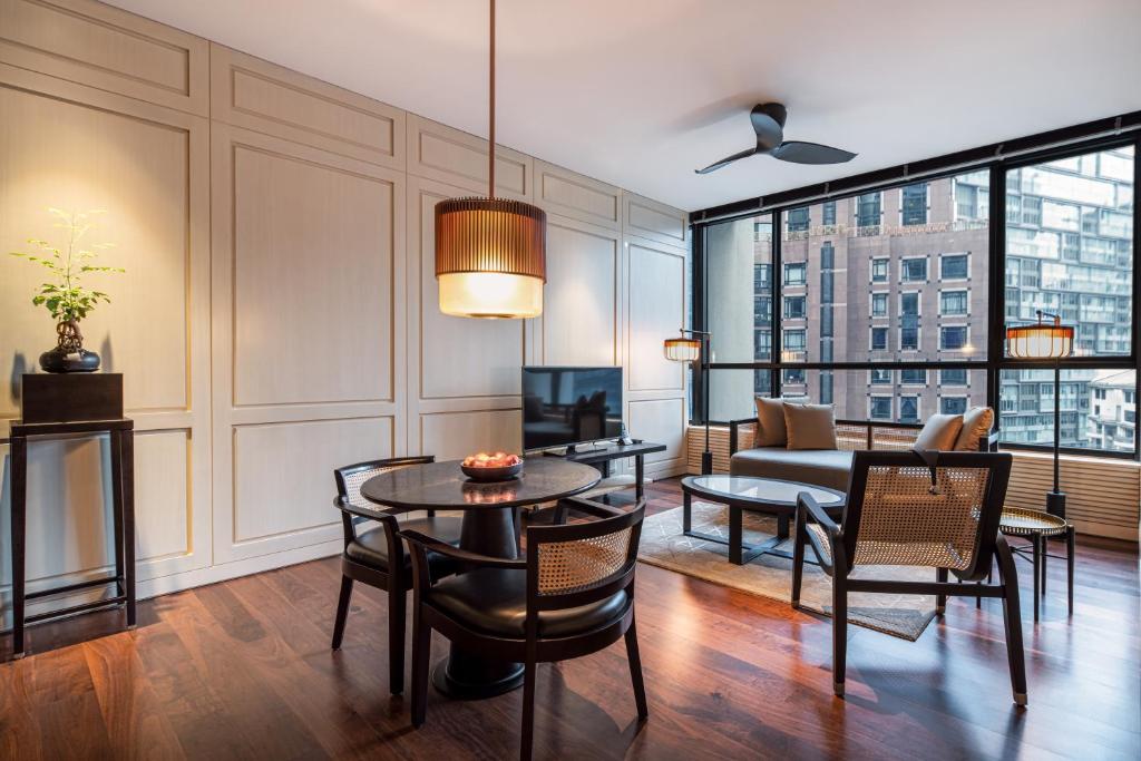 A spacious living room with dining seating, lounge chairs and broad city windows.