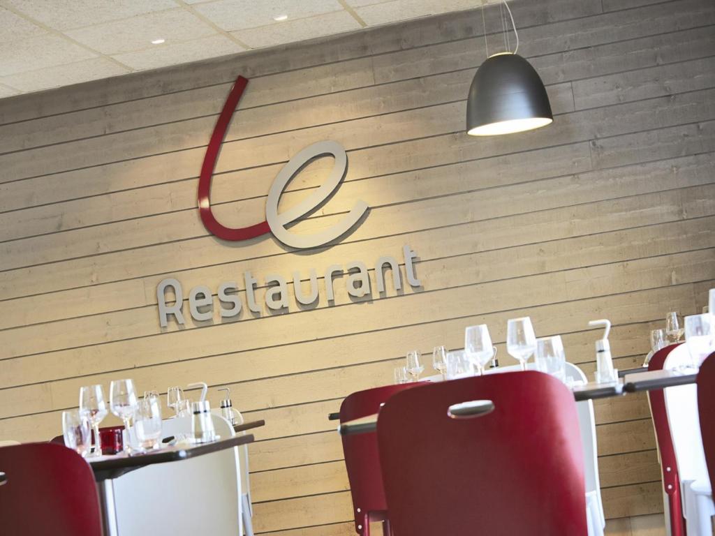 a restaurant with red chairs and a sign on the wall at Campanile Auxerre - Monéteau in Monéteau