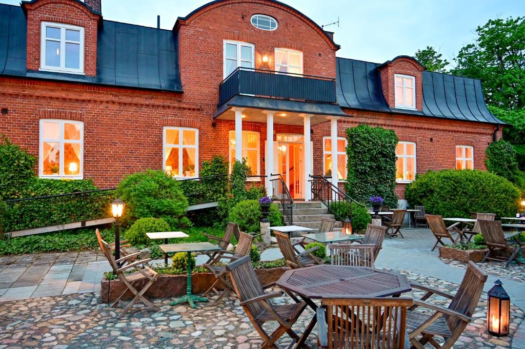 a brick building with chairs and tables in front of it at Kastanjelund in Yngsjö