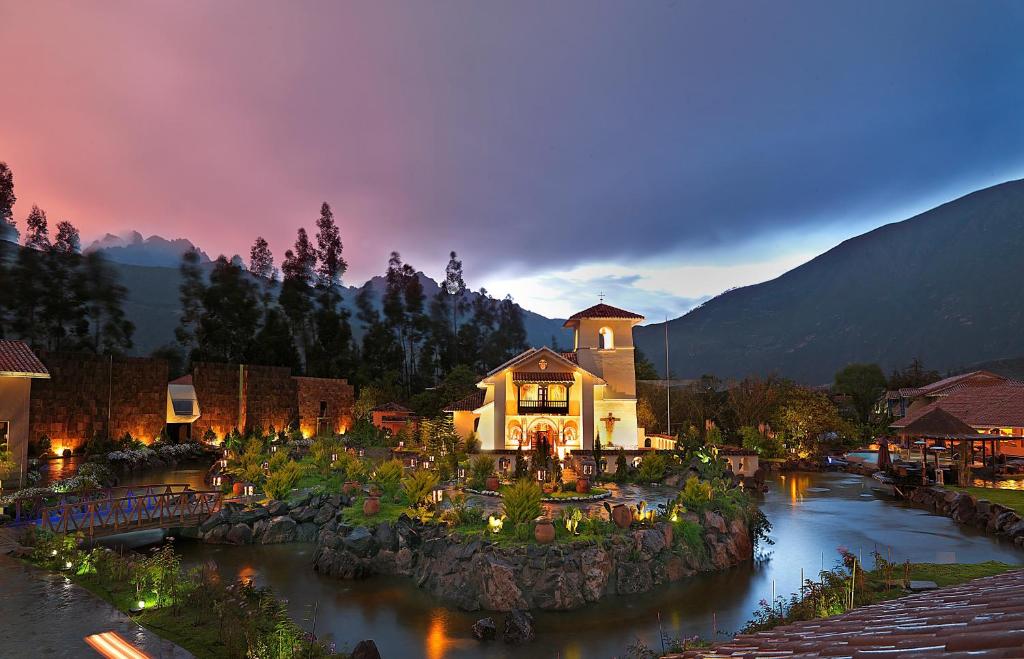 a building on a river in a town at night at Aranwa Sacred Valley Hotel & Wellness in Urubamba