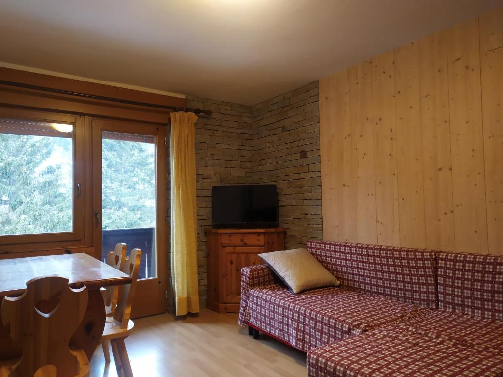 a living room with a couch and a tv at Mansarda Accogliente Falcade Dolomiti in Falcade