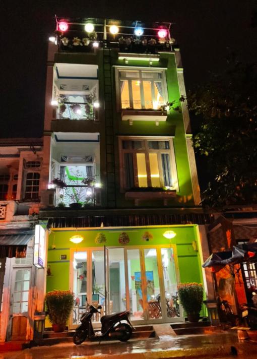 a green building with a scooter parked in front of it at An Na Bình Homestay in Hoi An