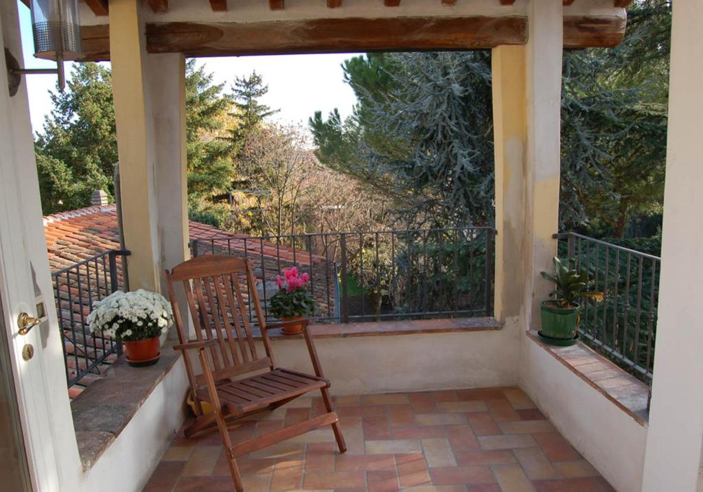 einen Holzstuhl auf einem Balkon mit Blumen in der Unterkunft Gaia in Lucca