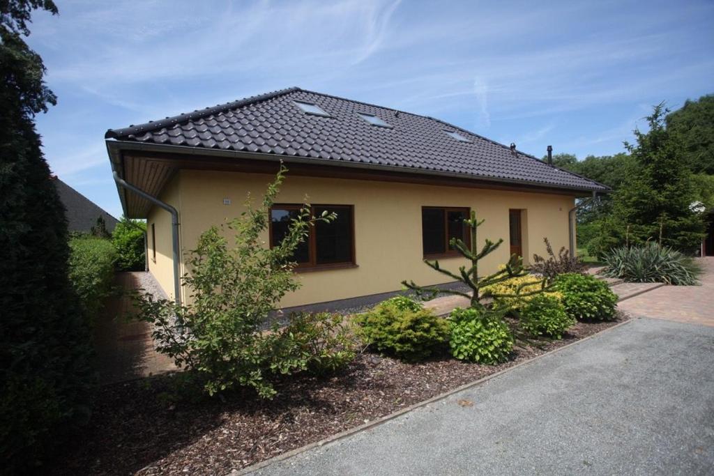 Pudagla的住宿－Ferienhaus Jule，一间黄色的小房子,有黑色的屋顶