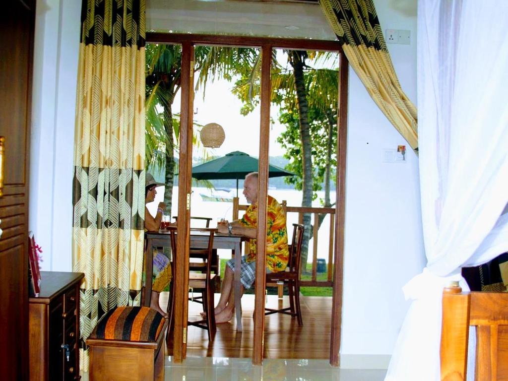 肯克拉的住宿－Koggala Lake view P&J Villa，坐在桌子上拿着雨伞的人