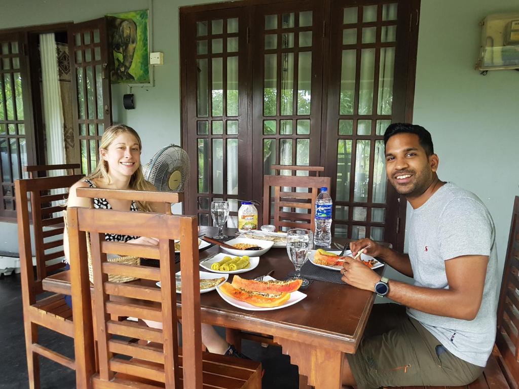 威爾帕圖的住宿－Wilpattu homestay by Ceylon group，坐在餐桌旁吃饭的男人和女人