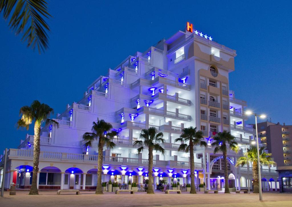 un bâtiment blanc avec des lumières bleues sur lui dans l'établissement Hotel Los Delfines, à La Manga del Mar Meno