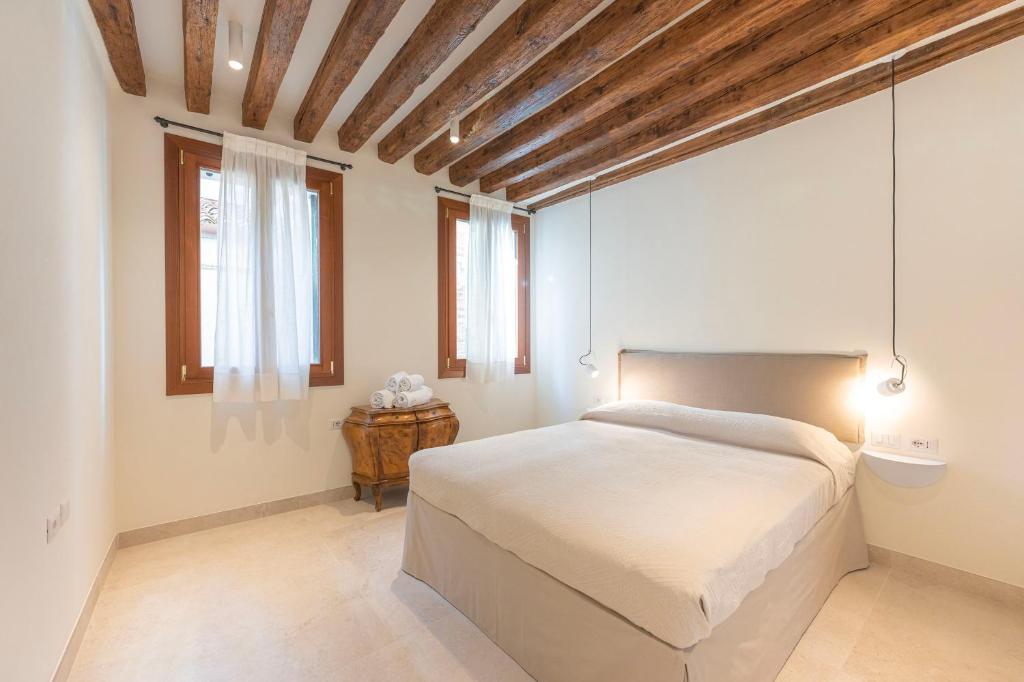 ein Schlafzimmer mit einem weißen Bett und einer Holzdecke in der Unterkunft Grifalcon D'Oro - Centro Storico in Venedig