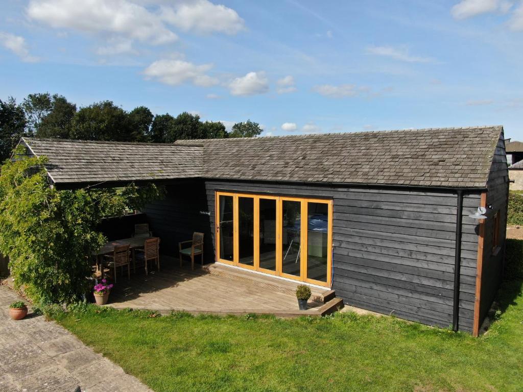 a small black shed with a deck in the grass at Pool House, farm stay in Brackley