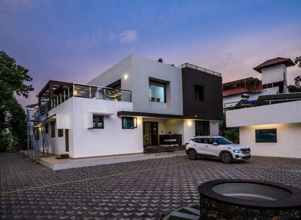 a white car parked in front of a house at Nadhiyoram River Retreat in Cochin