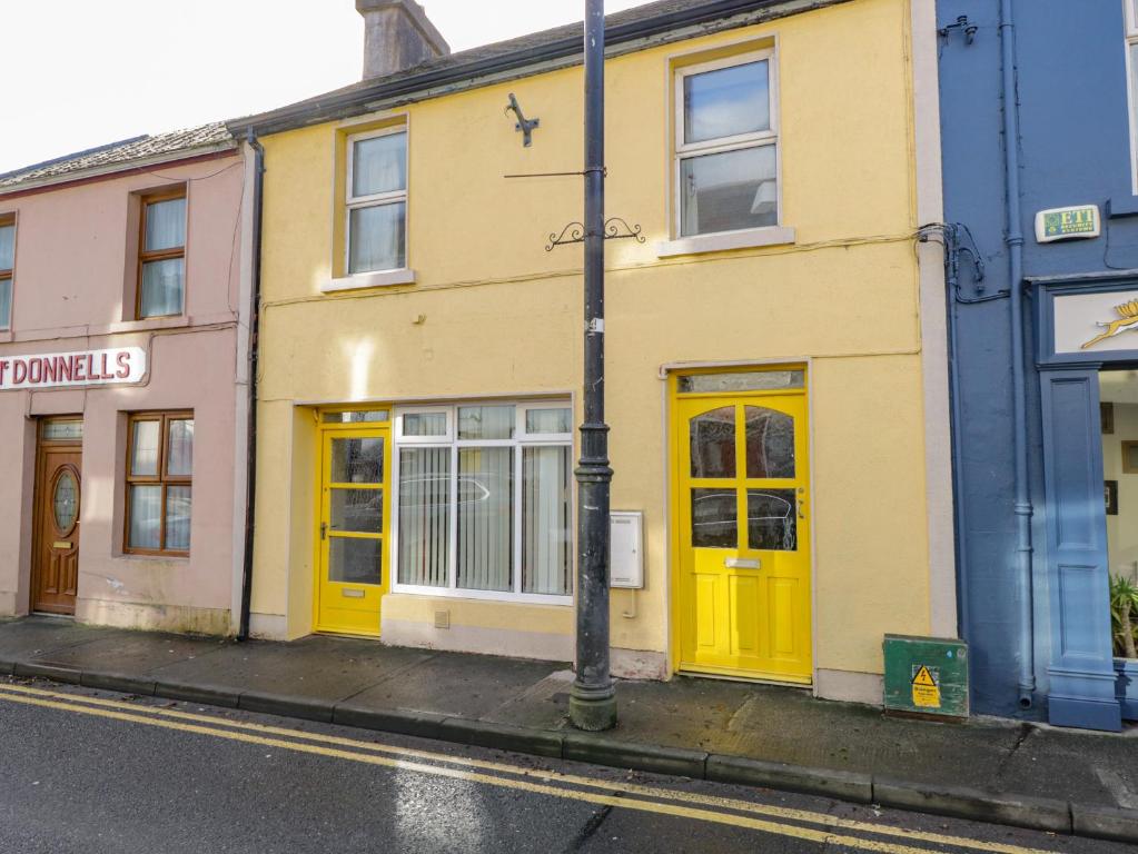 uma fila de edifícios com portas amarelas numa rua em Glebe House em Ballinrobe