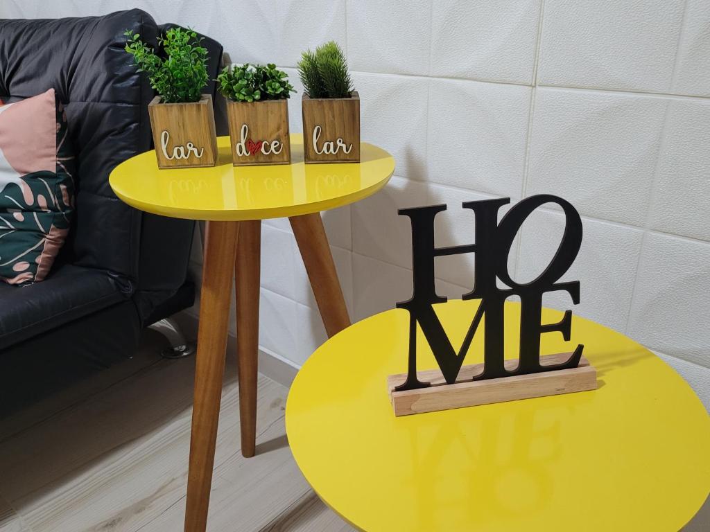 a yellow side table with plants on it next to a couch at Apto inteligente com Alexa, Wi-fi e Smart TV. in Praia Grande