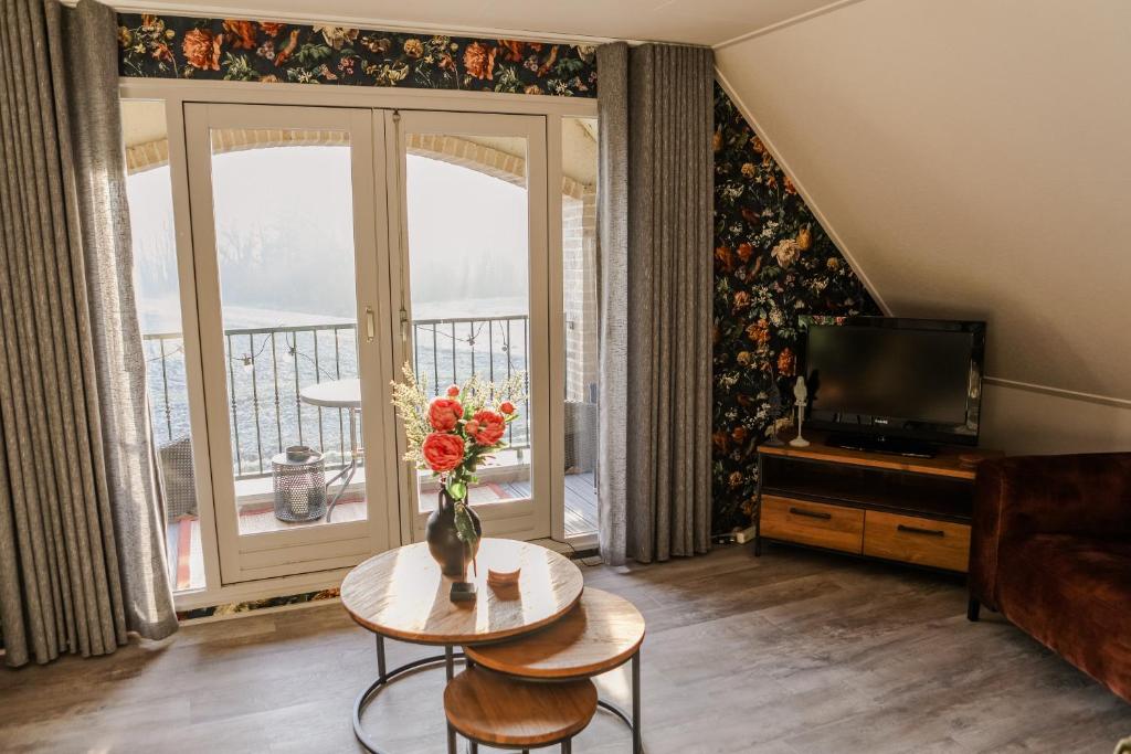 ein Wohnzimmer mit einem TV und einem Tisch mit Blumen in der Unterkunft Ruim en landelijk appartement in Wolphaartsdijk
