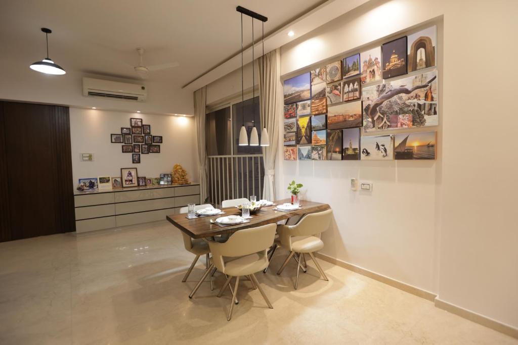 Artist House 3BR By Flora Stays في مومباي: غرفة طعام مع طاولة وبعض الصور على الحائط