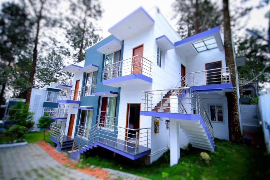 ein weißes und blaues Haus mit blauen Treppen in der Unterkunft GV Resort in Yercaud