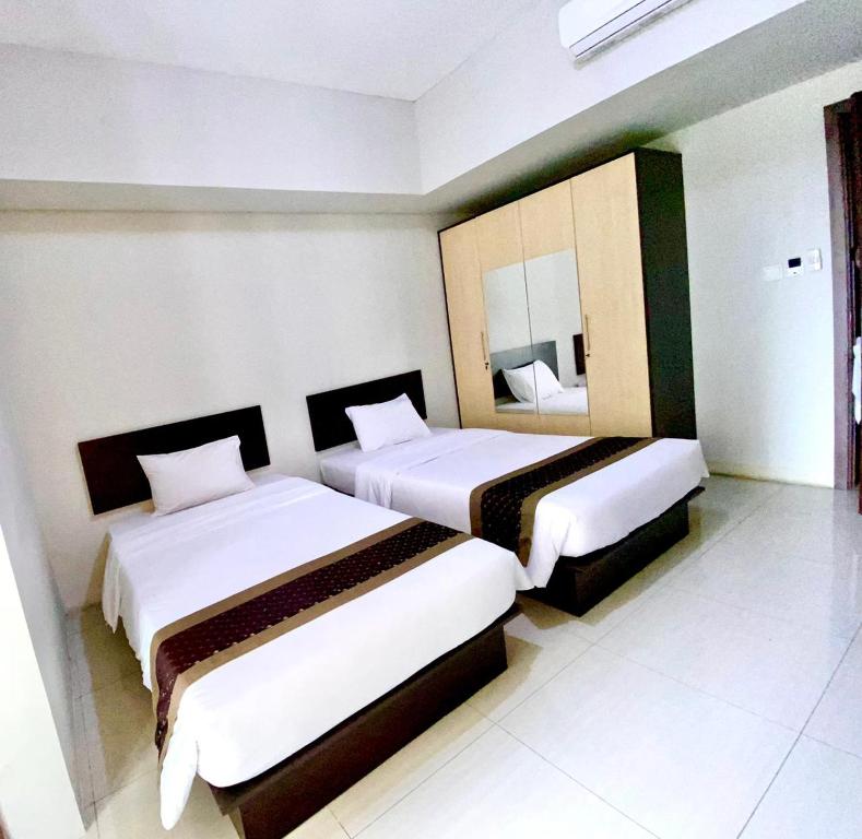 a hotel room with two beds and a mirror at Skyland City Hotel Jatinangor in Cilimus 2