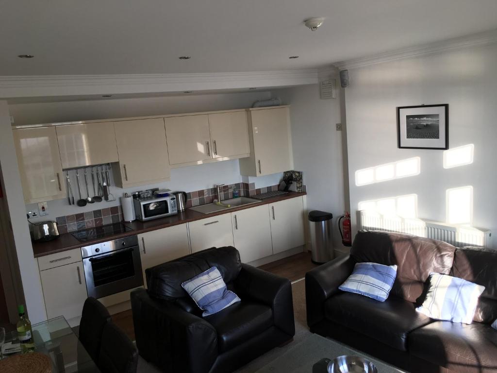 a living room with two couches and a kitchen at Southover Beach in Woolacombe