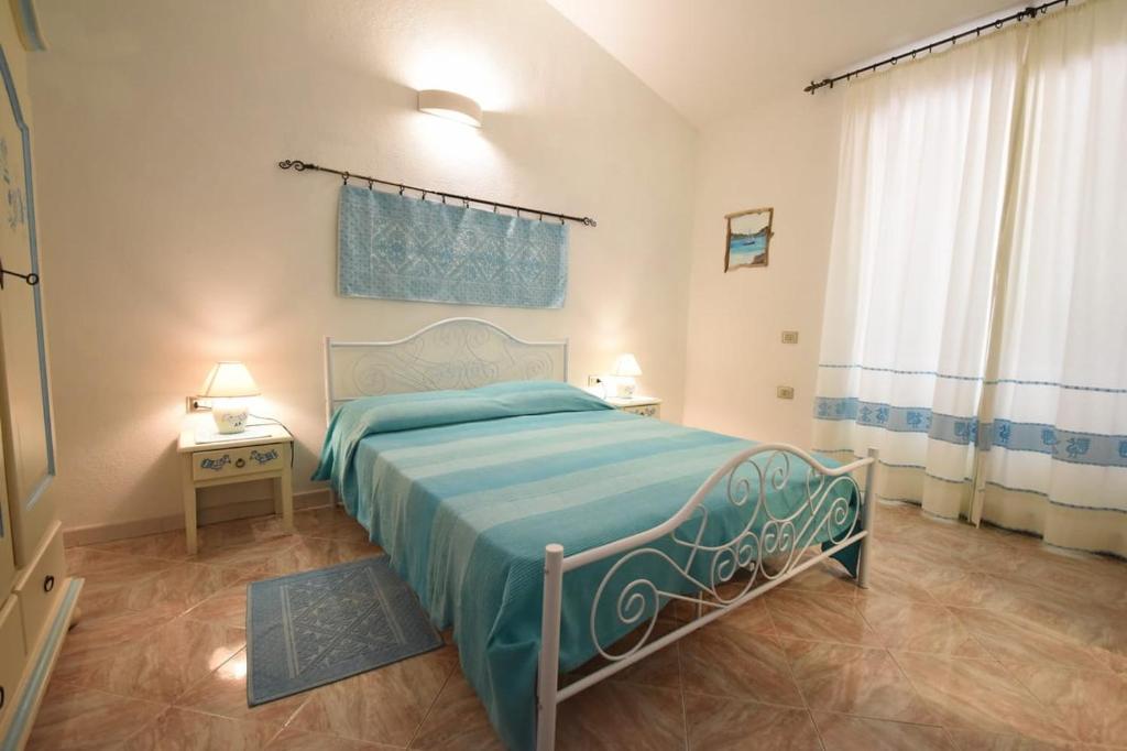 a bedroom with a bed with a blue blanket at Villetta a schiera in La Maddalena