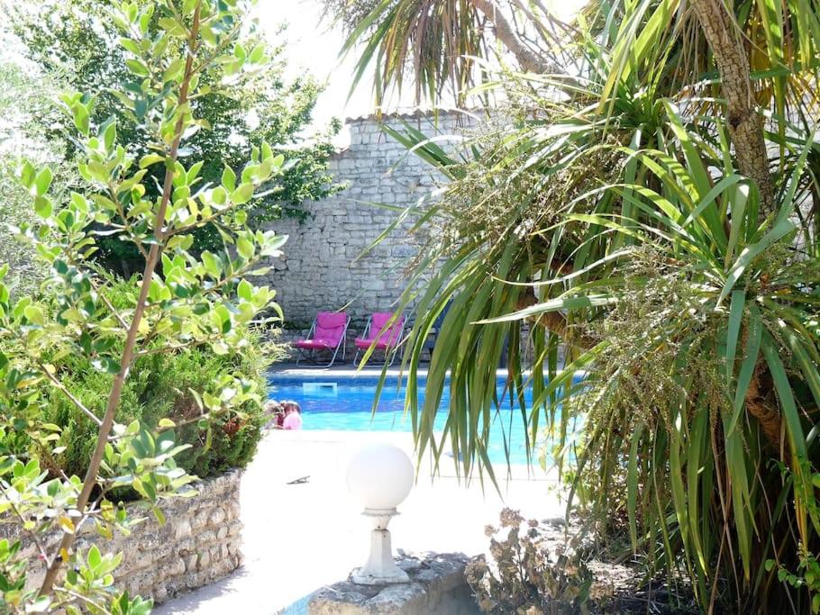 a swimming pool in a garden with palm trees at Villa del Ré 6 in La Flotte