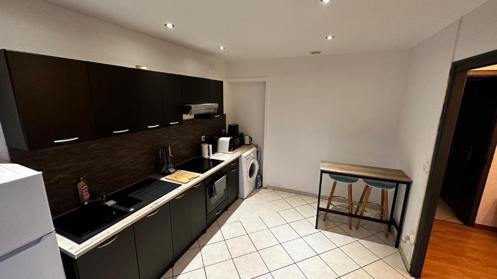 eine Küche mit schwarzen Schränken und einem weißen Gerät in der Unterkunft LA VILLA DEKO - Appart2 - Université et Hôpital in Beuvry