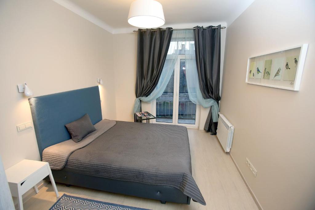 Cathedral Apartments في فيلنيوس: غرفة نوم بسرير ازرق ونافذة