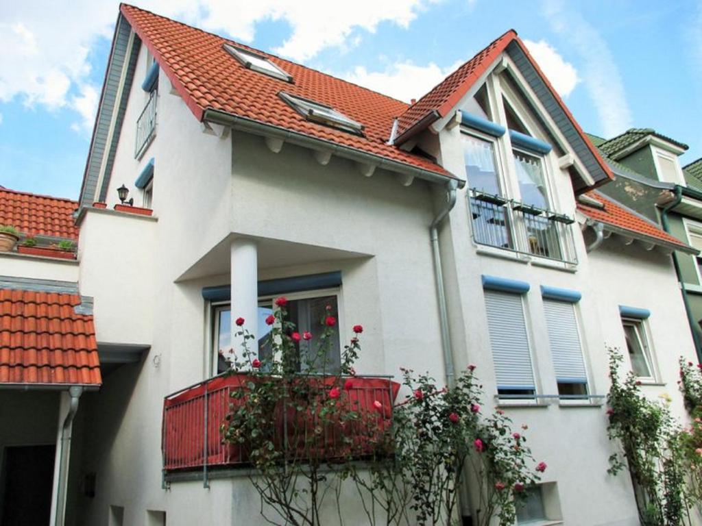 a white house with a red balcony with roses at Ferienwohnung Haas in Lauda-Königshofen