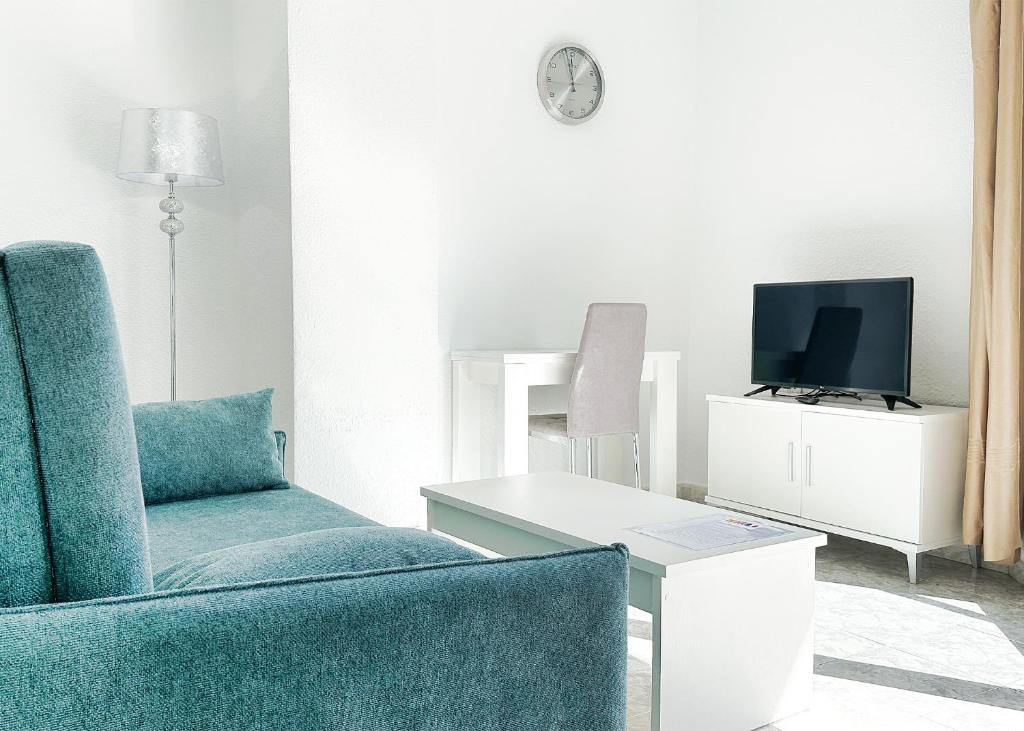 ein Wohnzimmer mit einem blauen Stuhl und einem TV in der Unterkunft Skol 131 - Studio at Skol Building in Marbella centre with sea views. in Marbella