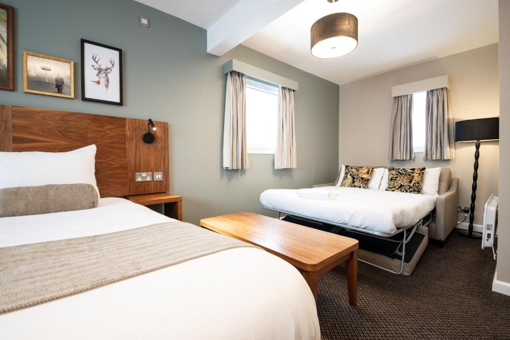 um quarto de hotel com duas camas e uma mesa em The Springfield Inn by Innkeeper's Collection em Lowdham